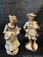 Front view of porcelain boy and girl figurines holding musical instruments
