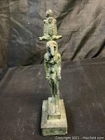 Front view of the Egyptian statue showing the standing figure with bird head and seated figure above its head.