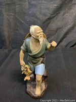 Full front and side view of fisherman statue holding fish with black background
