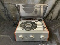 Front view of Jensen record player with closed dust cover showing the turntable and three control knobs on front face.