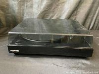 Side view of Cornell record player with clear dust cover closed, black base visible with Cornell nameplate.