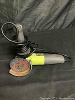 Ryobi angle grinder saw with attached power cord and one abrasive cutting blade showing rust and wear.
