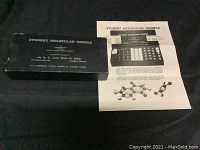 Closed box labeled Student Molecular Models with instruction sheet beside it on black background.