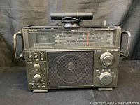 Front view of black rectangular Venturer radio showing speaker, tuning scales, control knobs and switches