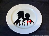 Photo showing the full collector plate with black silhouettes of two war veterans and the Canadian flag accent on shoulder.