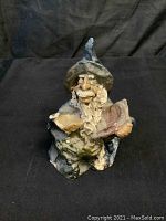 Front view of warlock statue holding open book, details of painted beard, hat, and robe visible