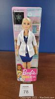 Front view of Barbie doll dressed as a doctor in original packaging with medical themed background