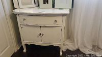 Front view of antique white painted wooden dresser showing drawer and cabinet doors, distressed wear visible