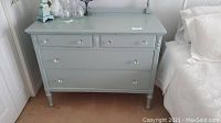 Front view of the blue antique dresser including top surface and drawers with knob handles