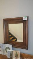 Front view of the rectangular mirror showing the thick wooden frame with a reddish-brown finish, measuring 23x25 inches.