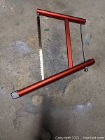Image showing the front view of the red aluminum framed backpacking hand saw with metal blade.