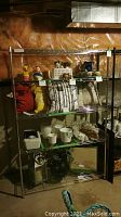 Full view of the assembled silver metal baker's rack shelf with various objects on shelves showing scale and condition.