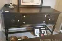 Front view showing 2 drawers in middle section and cupboard doors on each end with decorative knobs and ornate carvings.