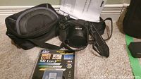 Nikon Coolpix L105 camera with carrying case and memory card on carpet.