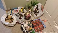 Overview of Christmas decor and crafting materials including pine cones, greenery sprays, and gift bags arranged on the floor
