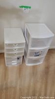 Photo of two plastic storage drawers, one with four smaller drawers and one with three larger drawers, both white.