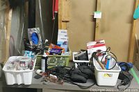 Overview of table with assorted tools, containers with small nails, screws, tape, safety glasses, and black tool bag