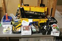 Full view of toolkit and tools on table showing toolbox, baskets of tools, clamp, tapes, and boxes.