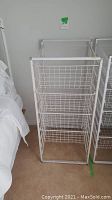 Front view of white wire storage unit with four wire mesh drawers, showing the rectangular frame and drawers front opening.