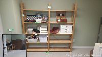 Full front view of the wooden shelving unit with some storage containers and boxes on shelves, a mirror leaning against the wall beside it.