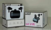 Five boxes of M30 Bluetooth 5.0 wireless earbuds, black color, showing one box opened with earbuds and charging case visible.
