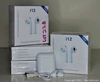 Five i12 TWS wireless stereo earbud boxes stacked with one charging case, a USB charging cable, and a pair of earbuds shown outside the boxes.