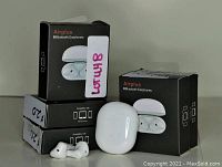 Four boxed Airplus Bluetooth Earphones with one charging case and one pair of earbuds outside the boxes for display.