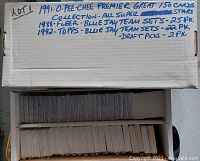 Cardboard box with handwritten details of lot contents listing 1991 O-Pee-Chee Premier superstar cards, 1988 Fleer Blue Jay team sets (25 packs), 1992 Topps Blue Jay team sets (22 packs), and 1992 Topps Blue Jay draft picks (2 packs).