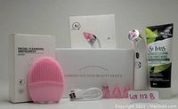 Photo showing pink facial cleansing instrument, white-pink comedo suction device with several suction tips, and tube of St. Ives facial scrub.