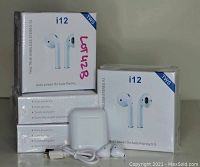 Four sealed boxes of i12 TWS earbuds stacked with one charging case and cable in front.