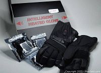 Photo of new intelligent heated gloves along with three silver rechargeable battery packs and black box labeled 'Intelligent Heated Glove'