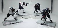 Four NHL player figurines: Jack Eichel, Ryan Suter, Aaron Ekblad, TJ Oshie. White bases with names and numbers, all in hockey playing poses.