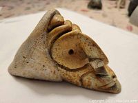 Close-up view of the carved abstract sculpture showing the shape, texture and spiral design with natural speckled coloration.