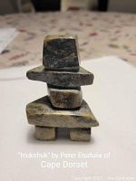 Front view of the carved stone Inukshuk sculpture showing stacked geometric forms and natural stone colors.