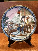Front view of the collector's plate showing detailed artwork of a traditional Chinese woman seated playing a musical instrument indoors with ornate decorations and window with plants in the background.