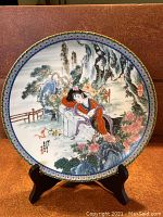 Front view of the porcelain collectors plate showing the detailed hand-painted design of a resting beauty in a traditional garden setting, displaying vibrant colors and detailed artwork.
