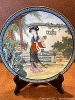 Front view of the Chinese collectors plate depicting a woman in traditional attire in a garden setting with detailed painting and decorative border.