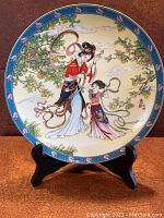 Front view of the collector's plate depicting the Apricot Fairy and a child in traditional Chinese attire with apricot tree in background, mounted on black stand.