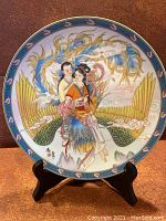 Front view of collectors plate, showing detailed artwork of couple and phoenix design with blue decorative border.