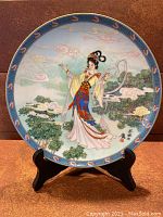 Front view of collectors plate with brightly colored traditional Chinese figure and decorative border.