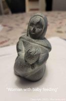 Front view of the stone sculpture showing the woman feeding a baby.