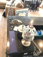 Wide shot showing assorted necklaces, crystal cut musical carousel, and jewel boxes on kitchen counter