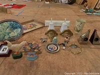 Lot showing two white wall mount lights, a blue floral pottery tray, a hexagonal Williamsburg pottery tray, cast-iron floral and rooster doorstops, small figurines, and decorative brass shelves.