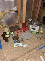 Overview image of lot showing multiple vintage kitchenware items arranged on plywood surface including glass dishes, wooden bowls, crocks, timers, and kitchenware boxes.