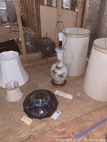 Full view of the lamp base with floral gold decoration and the four lampshades arranged around it.