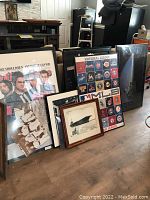 Overall view of multiple framed posters and photographs leaning against wall, including Beatles, baseball, and movie posters.