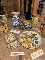 Hand painted Italian ceramic items with pitchers, teapot, large fruit plate and candy tray arranged on wooden surface.