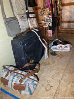 Photo showing a collection of purses including duffle bags, totes, and smaller handbags hanging and placed on the floor