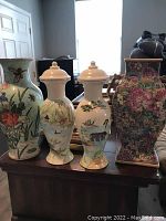 Four Asian themed vases on a wooden table showing varied floral and scenic designs.