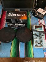 Overview of items including DieHard charger box, Alpine car speakers with protective grilles, UniRoss Universal 320 battery charger unit with cables, and some smaller items in background.